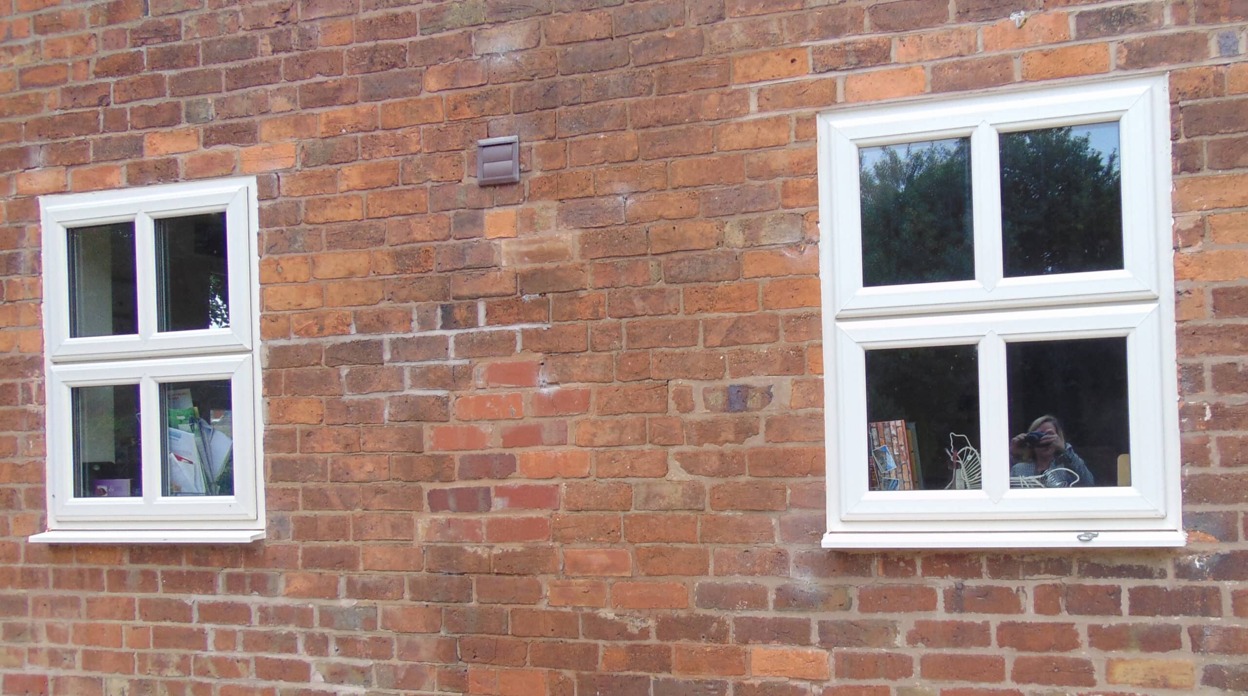 a traditional brick house with cream-colored upvc window frames, featuring a bay window and wooden porch. learn how to clean upvc window frames effectively to maintain their appearance and longevity.